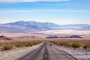 Looking down a long straight road at a vast Death Valley Landscape