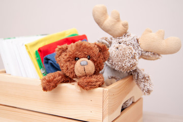 Donation concept. Donate box with kids clothes, books, school supplies and toys. Teddy bear and moose toy.