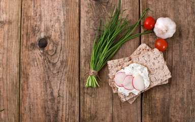 crispbread with quark and fresh chive, radish and tomatoes on a rustic wooden table - healthy...
