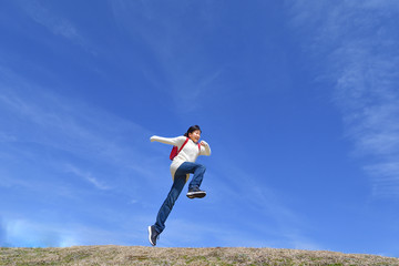 Fototapeta na wymiar 青空でジャンプする小学生の女の子（ランドセル）