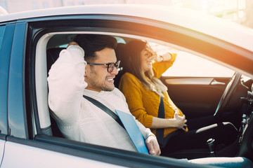 Naklejka premium Driving school or test. Beautiful young pregnant woman learning how to drive car together with her instructor.