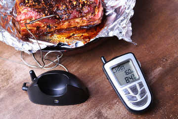 Grilled Steak in a pan and Wireless Remote Digital Cooking Food Probe Meat Thermometer For Grill on a black background. Copy space.