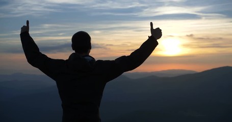 Man show thumbs on the top of the world.