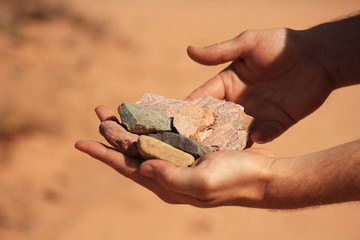 Manos de hombre sosteniendo piedras de diferentes colores en Purmamarca, Jujuy, Argentina