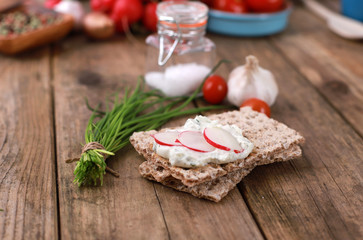 crispbread with quark and fresh chive, radish and tomatoes on a rustic wooden table - healthy breakfast with fresh herbs 