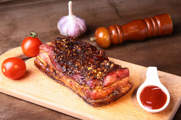 Sliced grilled pork ribs barbecue Striploin steak with chimichurri sauce and tomatoes on cutting board on dark background.