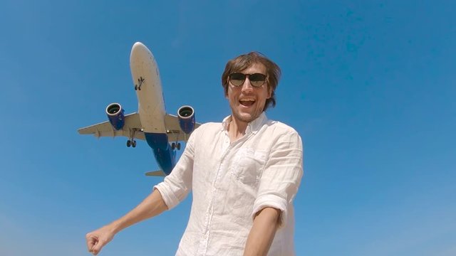 Superslowmotion shot of a young man making selfie video with a landing airplane flying above him