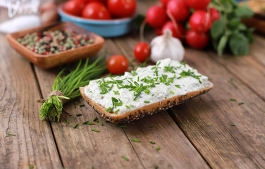 healthy breakfast -  wholemeal roll with quark and fresh chives, radishes and tomato on a rustic...