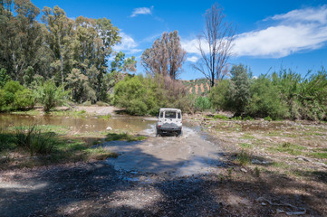Obraz na płótnie Canvas Rural Andalucia, Andalusia. Spain. 4WD vehicle crossing river. Back view.