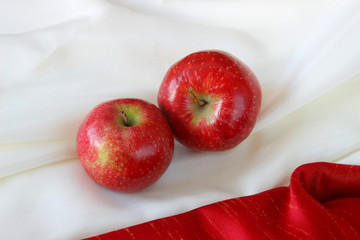 two red apples on a red and white tablecloth