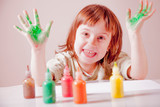 Green painted hands in a really happy beautiful little child girl. Beauty, art, childhood, color concept.