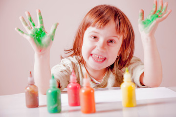 Green painted hands in a really happy beautiful little child girl. Beauty, art, childhood, color concept.
