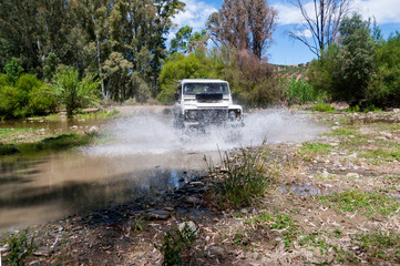Plakat Rural Andalucia. Spain. 4x4 vehicle crossing river causing water splashes. Front view.