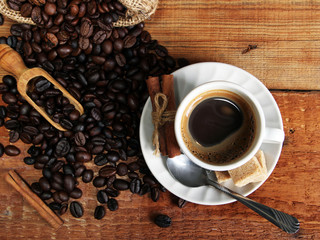 White Hot Coffee cup with Coffee beans, burlap sack and with cinnamon sticks on the wooden table. Top view
