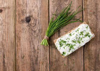  wholemeal roll with quark and fresh chives on a rustic wooden table - healthy breakfast - top view
