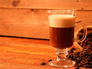 Irish coffee in glass on wooden table. Alcoholic or non-alcoholic coffee cocktail with liqueur, whiskey, cream. Cool drink. Easy Bartenders Recipes and Ideas. Copyspace