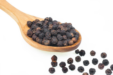 Close up heap of black pepper in wooden spoon, peppercorns isolated on white background, dried spice pepper corn concept