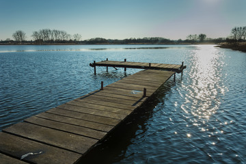 Obraz premium Jetty on the lake. Reflecting sunlight in water