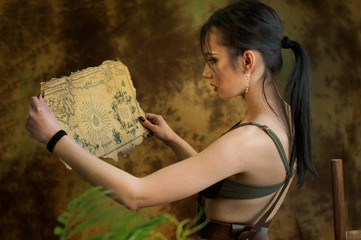 A young girl dressed up as a cosplay woman in jungle discovery old map with treasures