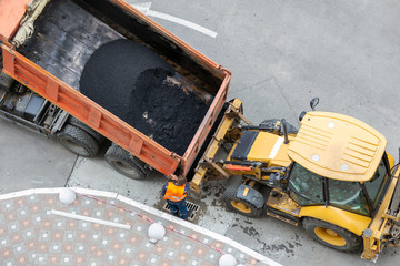Heavy industrial dump truck unloading hot asphalt .City road construction and renewal site © K-FK
