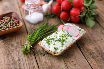 healthy breakfast - wholemeal roll with quark and fresh chive, radish  on a rustic wooden table 