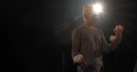 Juggler in the black studio and four balls in his hands.