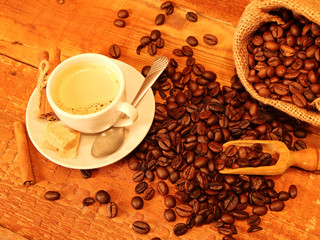 White Hot Coffee cup with Coffee beans, burlap sack and with cinnamon sticks on the wooden table. Top view
