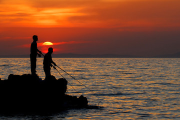 Fisherman on a shore at sunset