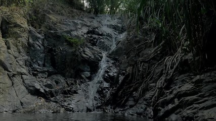 Close-up slow motion shot of small waterfall in the tropical rainforest jungle of Philippines. Small hidden rocky waterfall in jungle valley. Waterfall from a small mountain river in low mountains.
