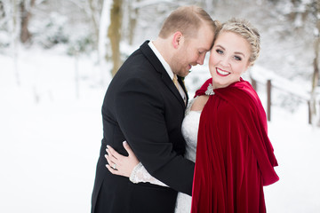 Stunning bride and groom embracing in snow covered woods