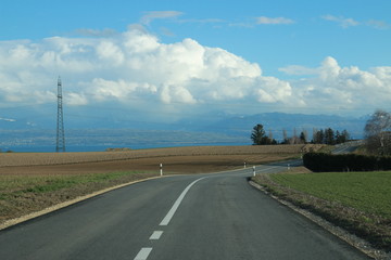 Fototapeta na wymiar Virage à droite sur une route vers le lac avec nuages 1/3