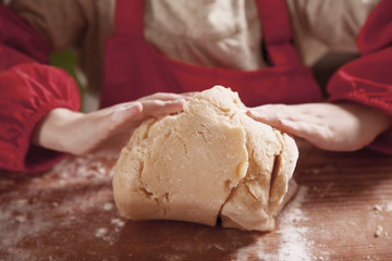 Hands of little cute child girl chef making the dough with flour on rustic wooden table. Homemade pastry for bread or pizza. Food and сooking process concept.