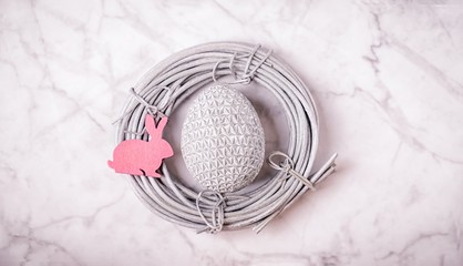 Silver easter egg and pink bunny in the silver nest on the marble background. 16:9. Minimal concept