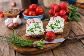 healthy breakfast -  wholemeal roll with quark and fresh chives, radishes and tomato on a rustic...