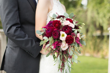 Bride and groom on wedding day with autumn floral bouquet