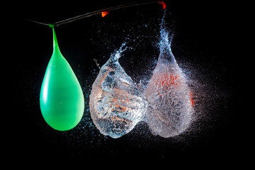 Amazing explosion big water color balloon bomb with splash  water on isolated  black background with flash. Сoncept of freezing moment of time.