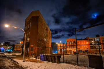 Urban winter street city night scene with vintage Chicago buildings an empty lot and the moon