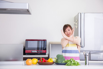 キッチンでバツサインする女性