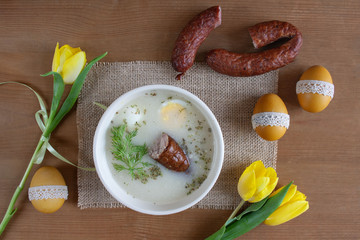  Wielkanocne śniadanie - żurek z jajkiemi i kiełbasą, obok pisanki, koszyczek ze świeconką