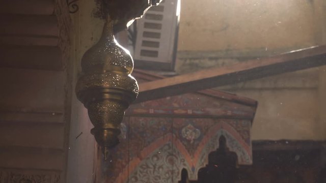 Street shot of carved cooper lamp hanging on the street of Fes city in Morocco. Medina atmosphere, dust in sun beam.