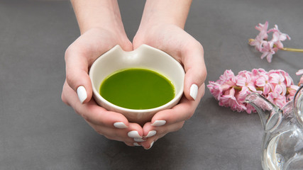 Hands holding a bowl with matcha tea