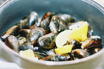 steamed mussels in a classic pot with some pieces of lemon