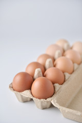 Chicken eggs are arranged in a gradient color tone in eco carton on white background.(perspective view)