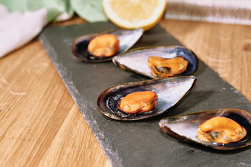 Fototapeta na wymiar Steamed mussels on slate table and wooden table