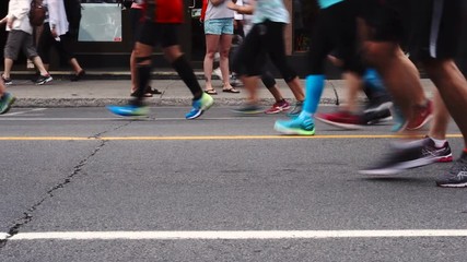 A big group of runners run by on the street during a marathon race