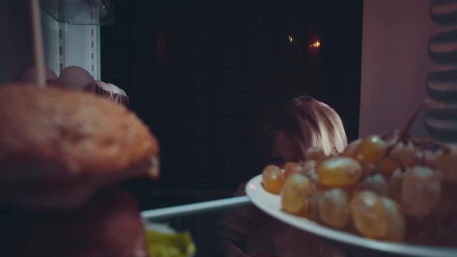 Little cute baby takes food out of the refrigerator at night, the problem of choosing between healthy and unhealthy food.Irregular nutrition and sleep disturbance.