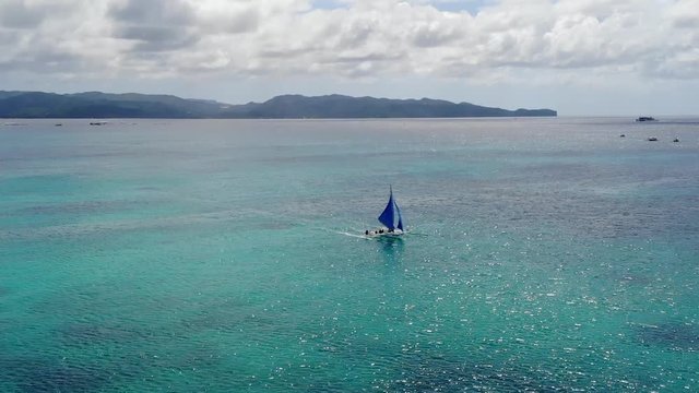 Trimaran Sailboat on Shimmering Turquoise Ocean Between Islands.