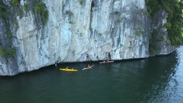 Gorgeous shot of kayakers moving along the side of a large cliff on the waters of Halong Bay,Vietnam.