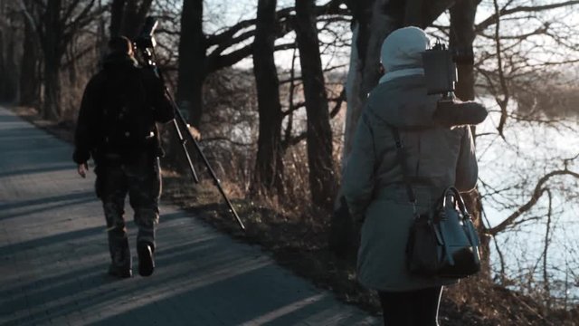 Photographer and filmmaker walking along the path next to the ponds during sunset