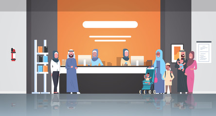 arabic patients in hijab standing line queue at hospital reception desk medical doctors consultation healthcare concept waiting hall clinic interior full length horizontal flat
